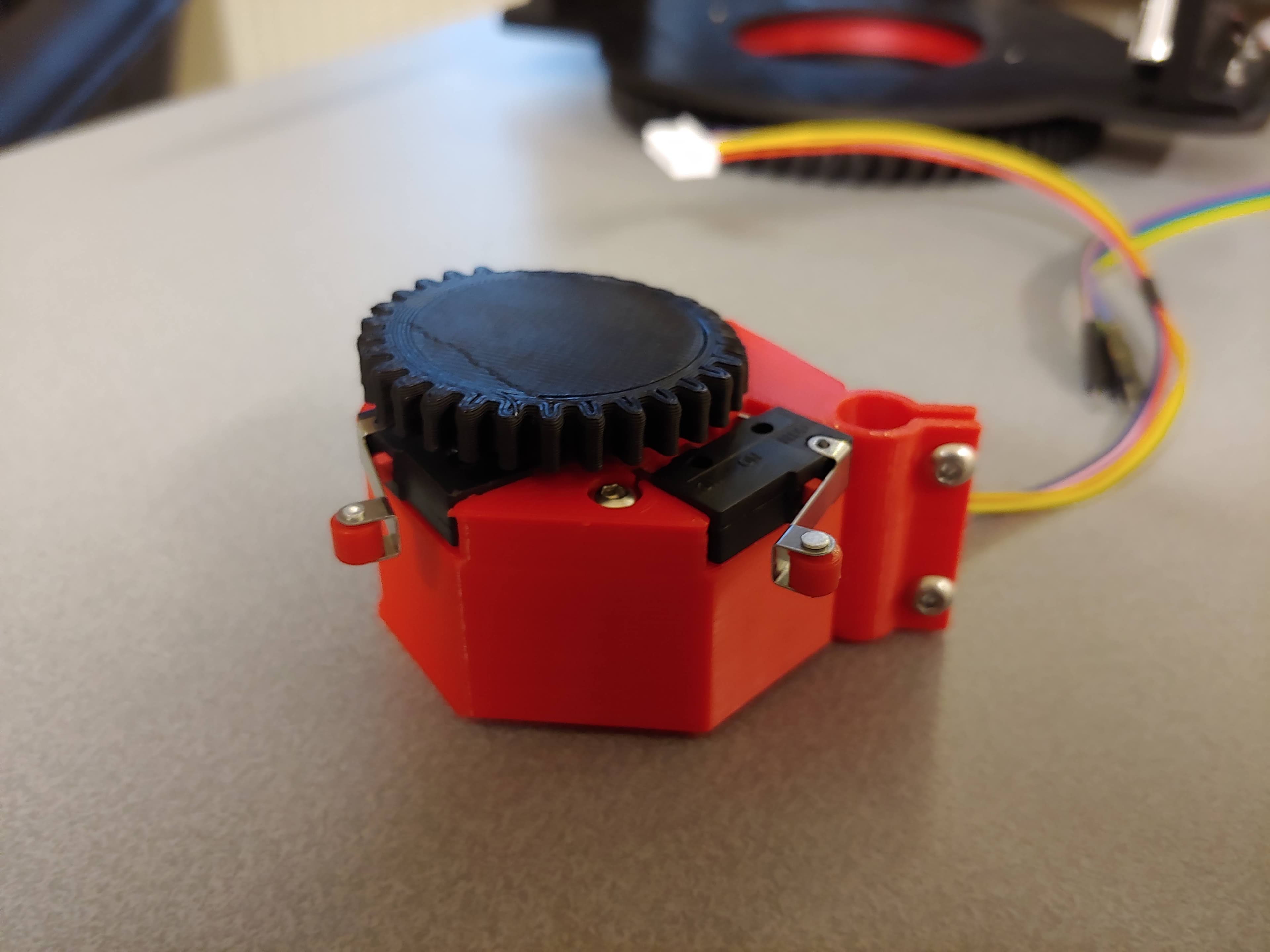 Small red 3D-printed mechanism with a wheel and microswitches
